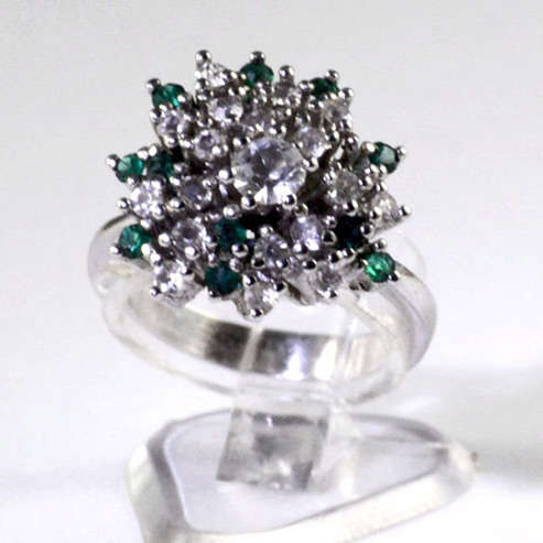 Silver plated ladies dress ring with a combined cluster of small bright created emeralds and white synthetic stones with a larger white centre stone