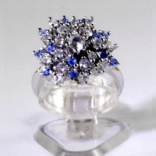 Silver plated ladies dress ring with a combined cluster of small bright created blue and white synthetic stones with a larger white centre stone